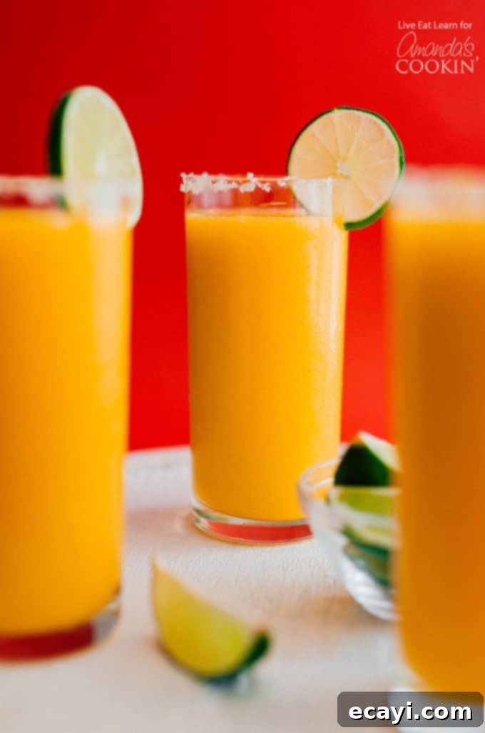 Refreshing Mango Margarita Slush: Your Perfect Summer Cocktail Three glasses full of mango margarita slush with a lime garnish