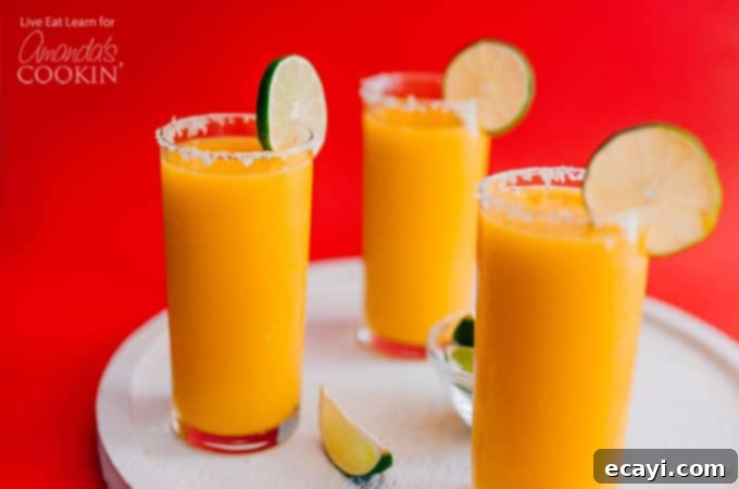 Perfectly garnished Mango Margarita Slush ready to enjoy Mango Margarita Slush in glasses with a salted rim and lime garnish.