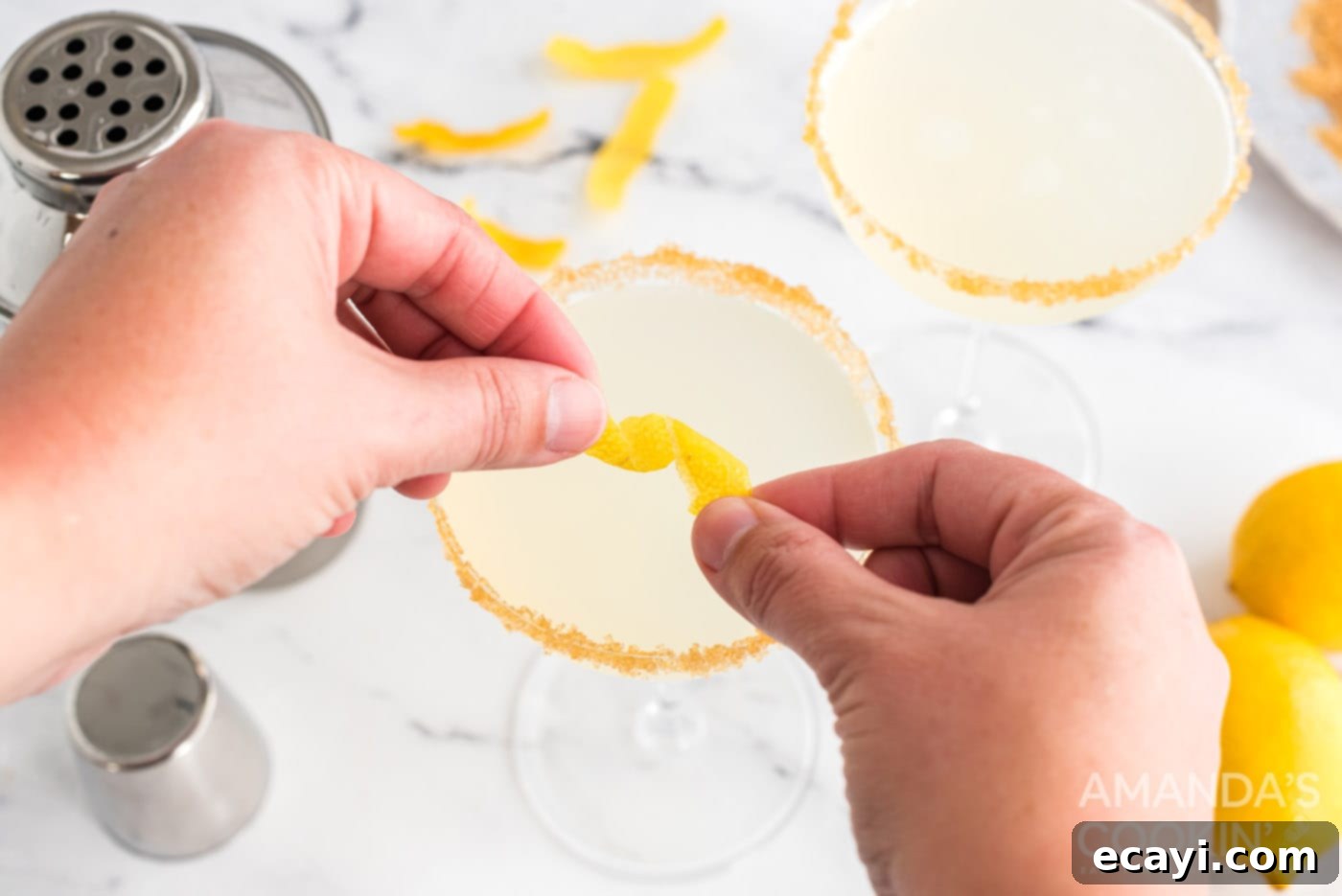 Sweet Tart Twinkle 9 Twisting a strip of lemon peel over a freshly poured cocktail.