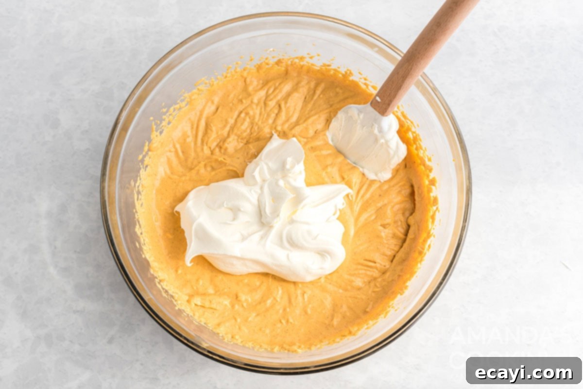 Dreamy No-Bake Pumpkin Perfection 8 Whipped topping gently folded into the pumpkin cheesecake batter with a spatula, creating a lighter, airier texture.