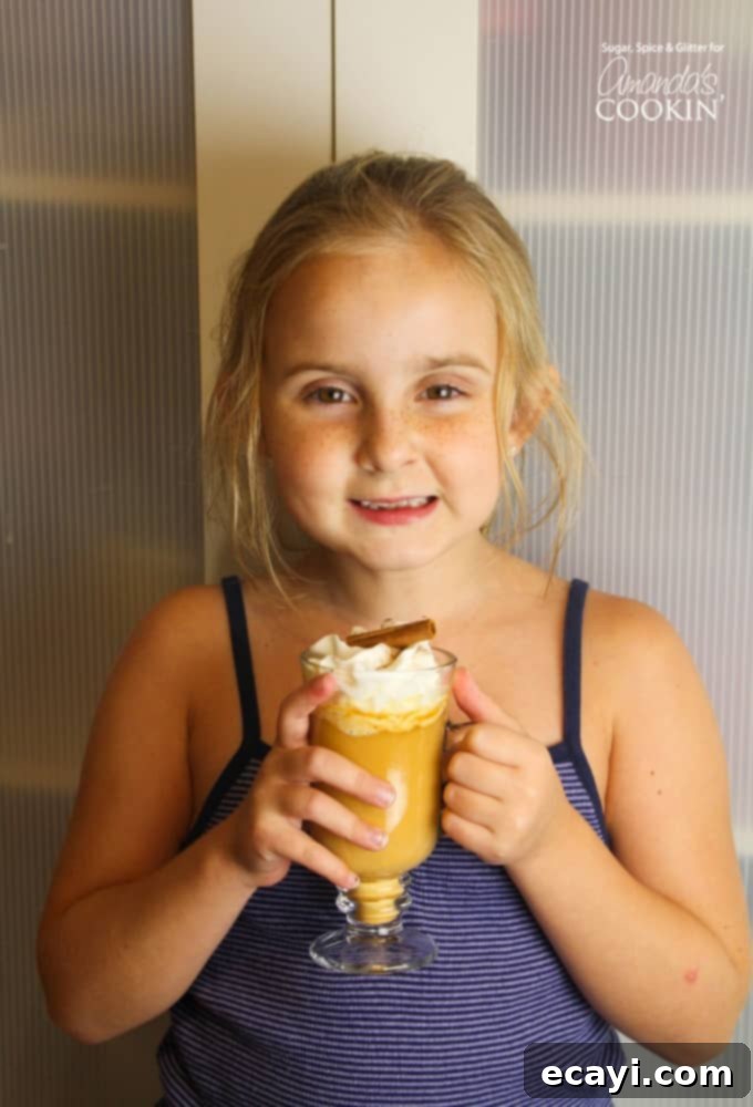 Delicious pumpkin spice hot chocolate the whole family will love! Girl holding pumpkin spice hot chocolate in a mug