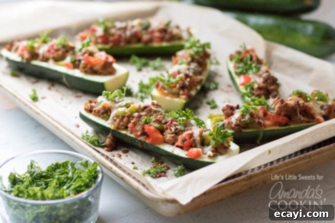 These colorful stuffed zucchini boats are a savory and delicious dinner packed with lean protein and a healthy serving of vegetables. Stuffing zucchini with lean ground turkey, fresh peppers, onions, and grated cheese makes for a tasty low-carb dinner and is a great way to use up all that garden zucchini! #zucchiniboats #stuffedzucchini #zucchinirecipes #lowcarbdinners #lowcarbrecipes #groundturkey #zucchini #amandascookin Pan of freshly baked stuffed zucchini boats
