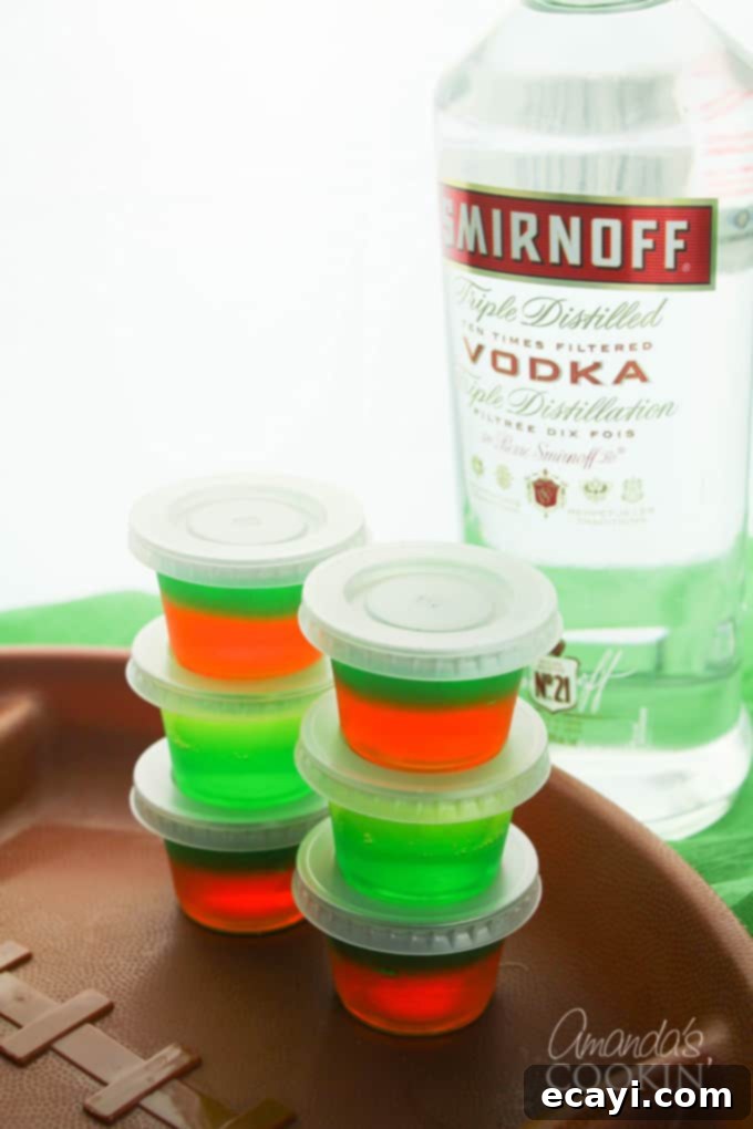 Love tailgating? Portable football jello shots are perfect for it! Watch the game at home or the stadium, these football jello shots are great! #jelloshots #footballjelloshots #footballteamjelloshots #footballfood #tailgating #tailgatingcocktails #sponsored #IbottaPartner #howtomakejelloshots #amandascookin Close-up of football jello shots in individual plastic containers with lids
