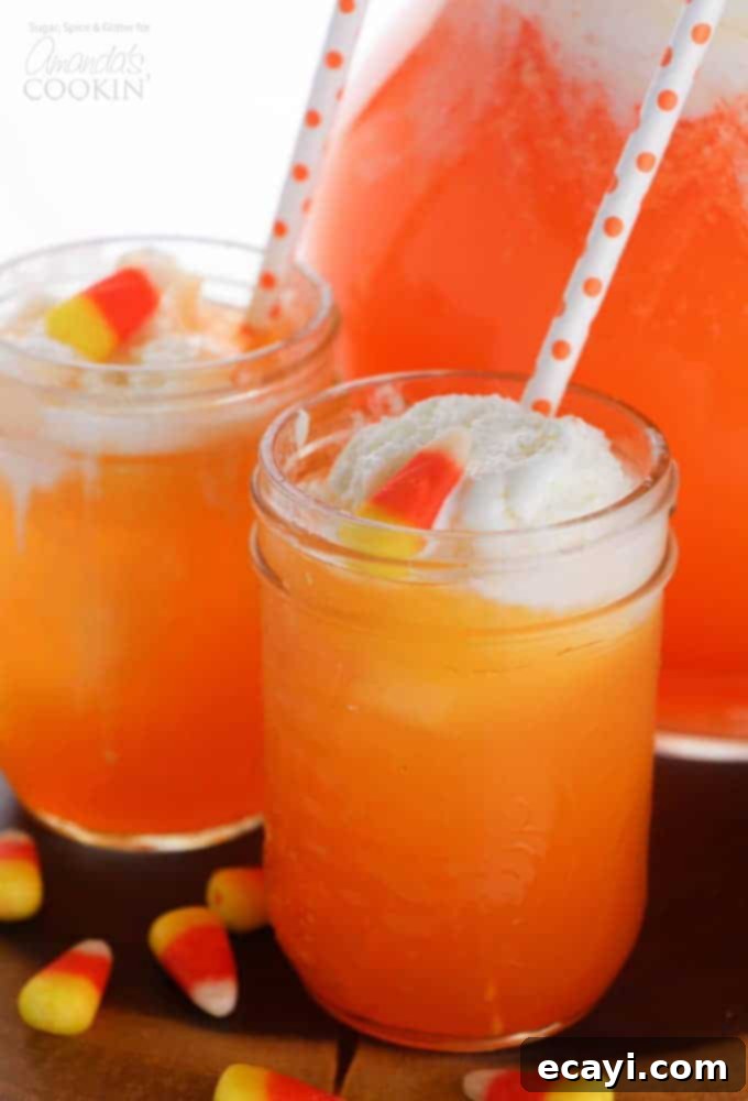 Candy Corn Punch: A festive, layered drink for Thanksgiving and fall parties! Vibrant Candy Corn Punch in a clear glass with straws, perfect for autumn festivities
