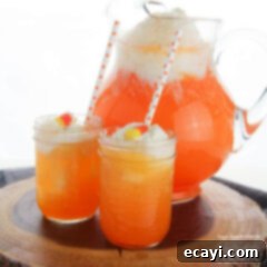 Ghostly Gradient Punch 5 Two glasses of festive Candy Corn Punch with a pitcher in the background, showcasing its delightful layers