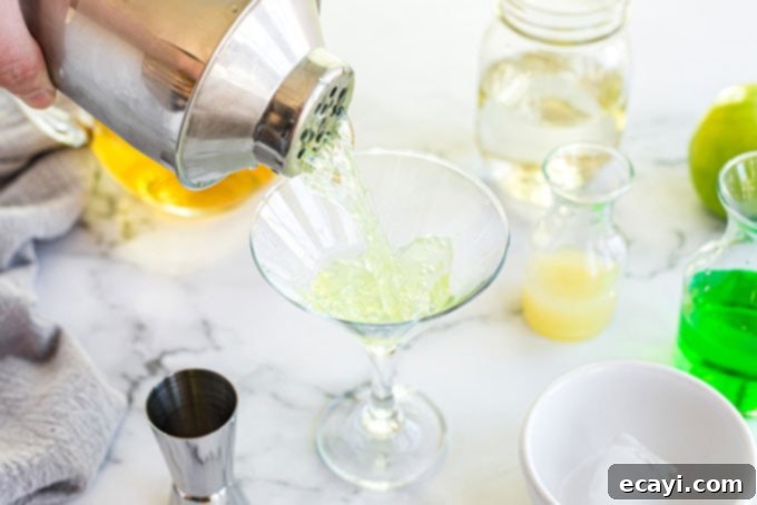 Crisp Apple Charm 6 Straining the freshly shaken Appletini cocktail into a chilled martini glass