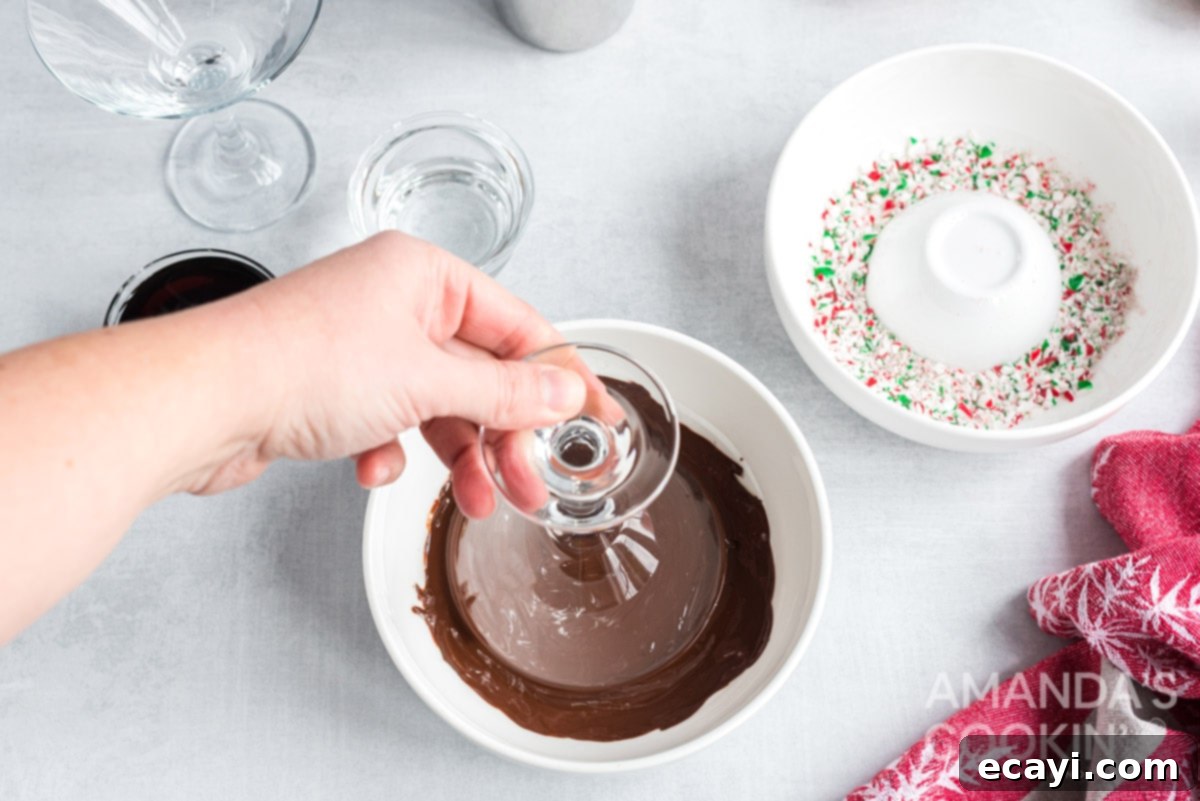 Carefully coating the martini glass rim with melted chocolate, the first step for a festive garnish. Dipping the rim of a martini glass into melted chocolate for a decorative edge.