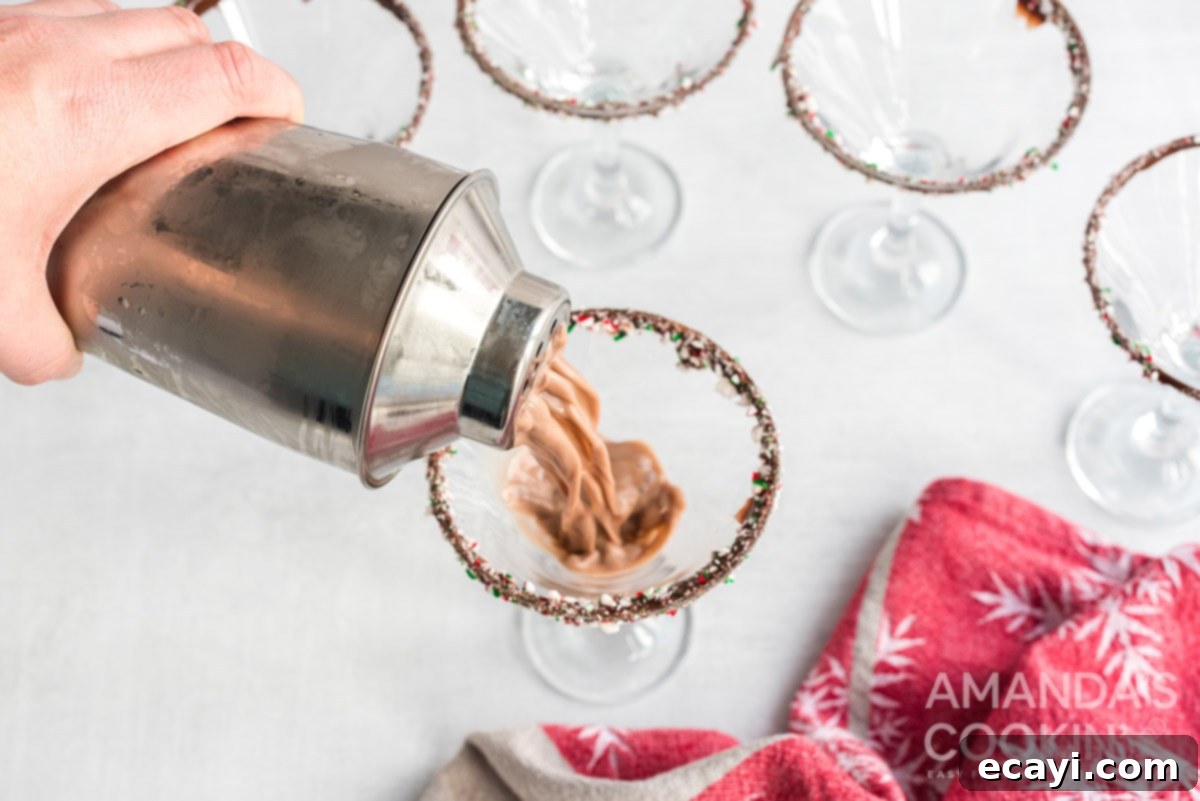 Serving the delicious Chocolate Peppermint Martini by carefully pouring it into a chilled, decorated glass. Pouring the freshly shaken Chocolate Peppermint Martini into a glass with a festive rim.