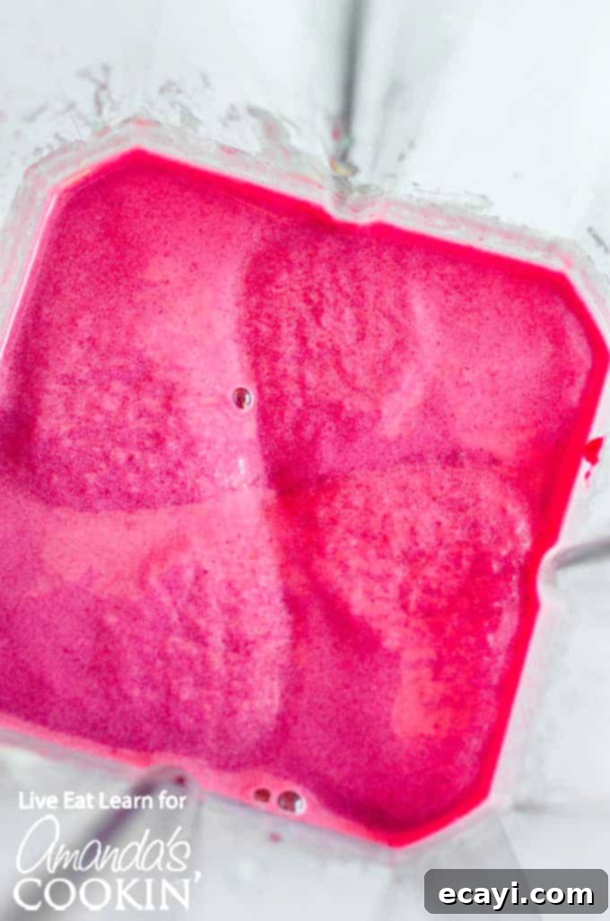 Strawberry Beet Glow 3 Mixing strawberry, beet, banana, and yogurt in a blender for a healthy smoothie