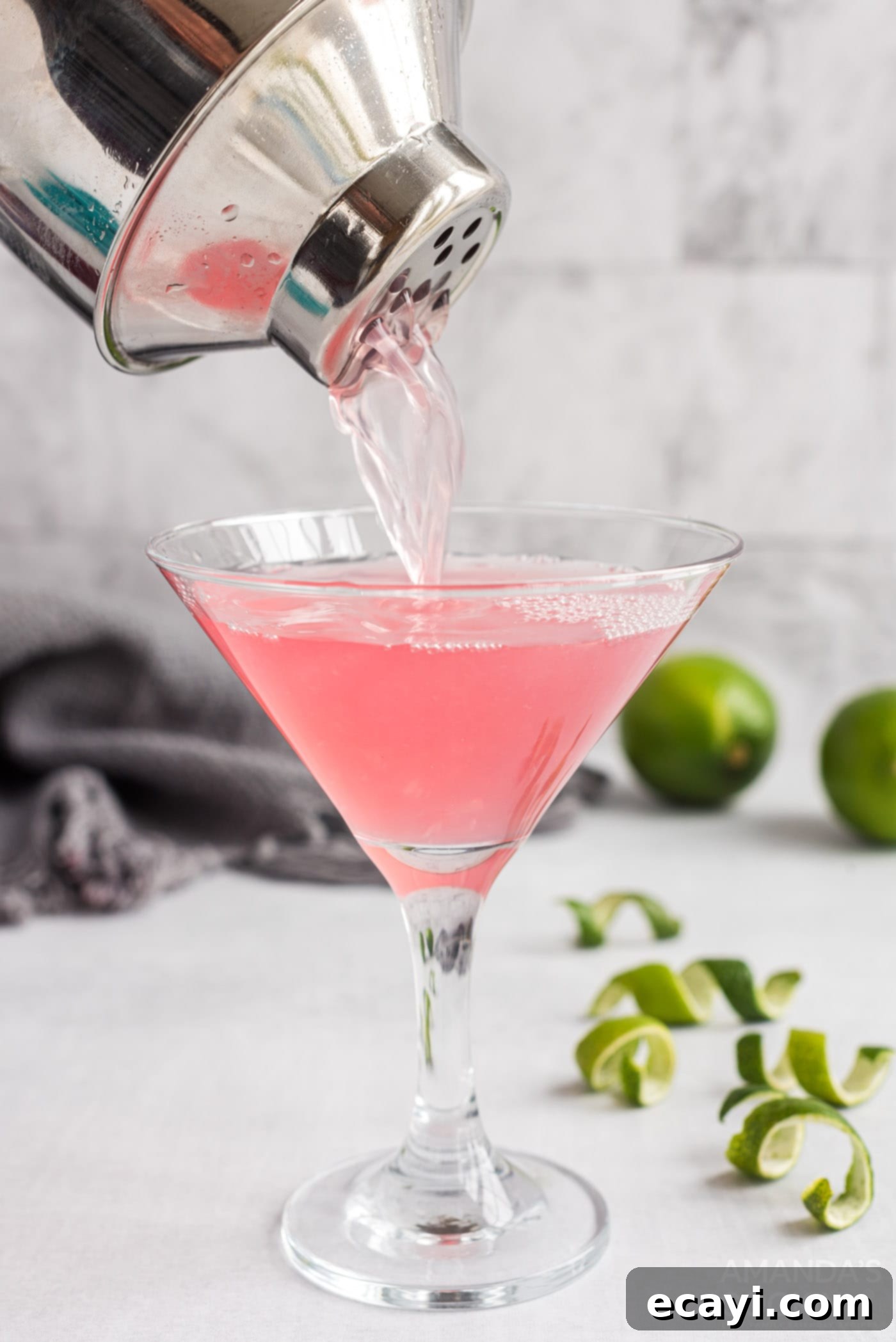 The Iconic Cosmopolitan Cocktail 6 Straining a vibrant pink Cosmopolitan cocktail into a chilled martini glass