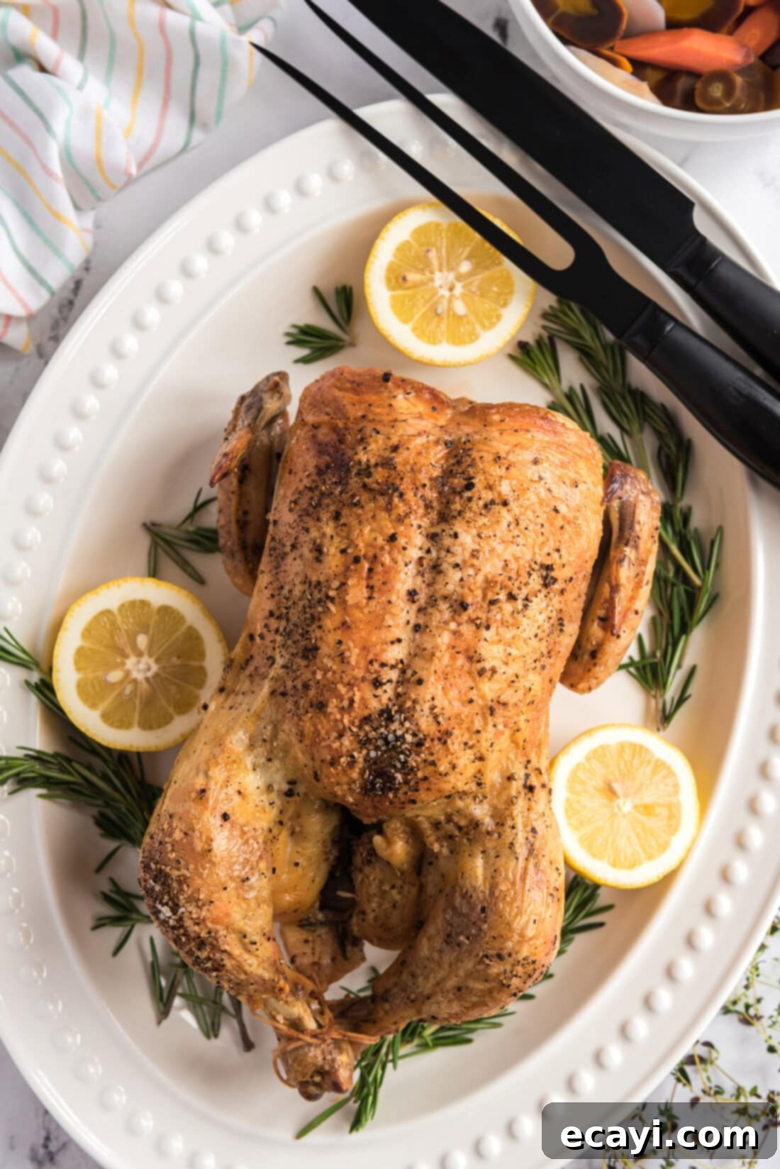 Golden Herb Roasted Chicken 2 Kızartılmış Tavuk, yanında oyma gereçleriyle birlikte bir servis tabağında