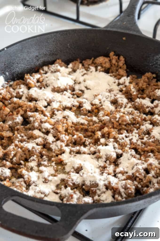 Hearty Country Gravy 5 Sausage crumbles in a skillet after flour has been added, forming a roux