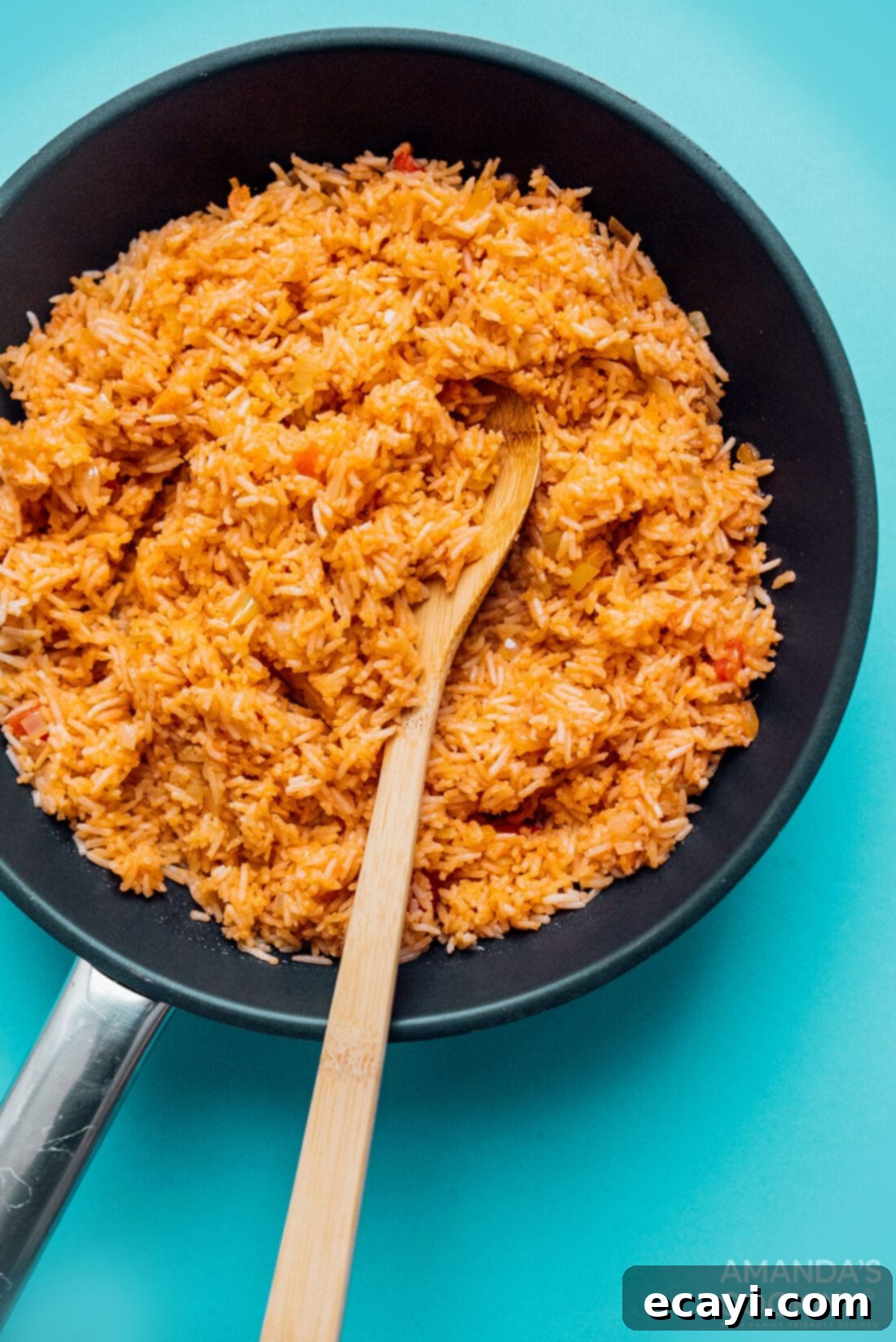 This Spanish rice recipe is a classic for good reason. A flavorful combination of onion, garlic, and salsa makes a side dish everyone loves. #mexican #spanishrice #dinnersides #sidedishes #vegetarian  A wide skillet filled with freshly made Spanish rice, showing its rich, reddish-orange color and fluffy texture.