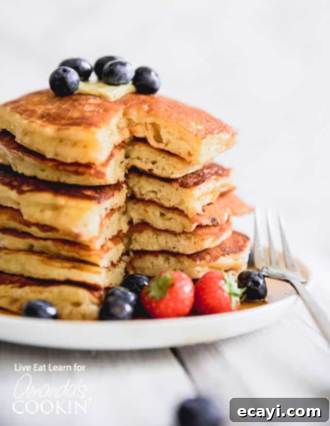 These classic buttermilk pancakes are fluffy, filling, and so delicious. Homemade pancakes are easier than you thought, so throw away that box mix! #breakfast #breakfastrecipes #buttermilkpancakes #pancakes #homemadepancakes Fluffy Homemade Buttermilk Pancakes stacked high with fresh berries and syrup.