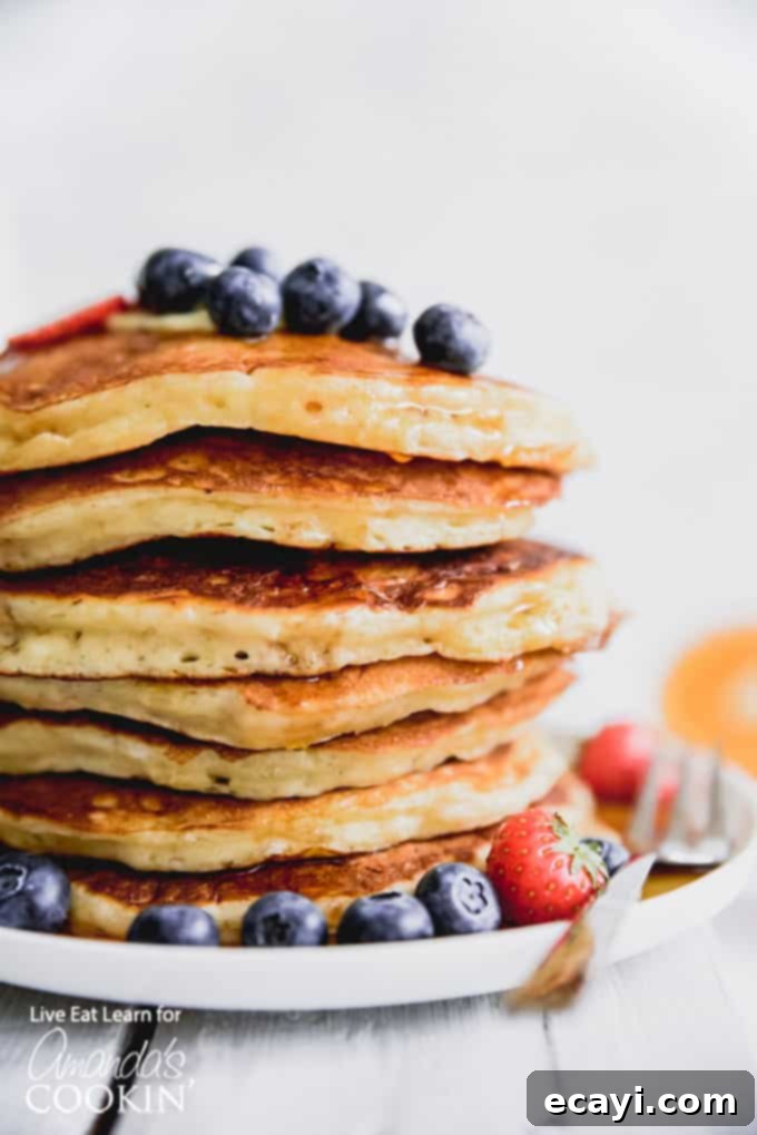 These classic buttermilk pancakes are fluffy, filling, and so delicious. Homemade pancakes are easier than you thought, so throw away that box mix! #breakfast #breakfastrecipes #buttermilkpancakes #pancakes #homemadepancakes A vibrant display of fluffy buttermilk pancakes, generously topped with fresh blueberries and strawberries.