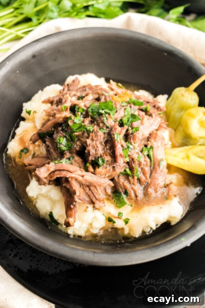 This Mississippi pot roast is slowly cooked in the crockpot until it's fall-apart tender then served with a rich gravy made w/ ranch & pepperoncini peppers. A hearty bowl of Mississippi Pot Roast served with creamy mashed potatoes, showcasing the tender, shredded beef and rich gravy.
