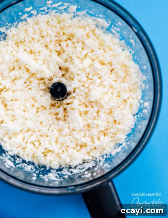 Quickly Make Cauliflower Rice for a Low-Carb Risotto Base – Easy and Healthy. #risotto #lowcarb #asparagus #cauliflowerrice #cauliflowerrecipes #dinnerrecipes #garlic Cauliflower florets being processed into 'rice' in a food processor, a key step in preparing low-carb cauliflower risotto.