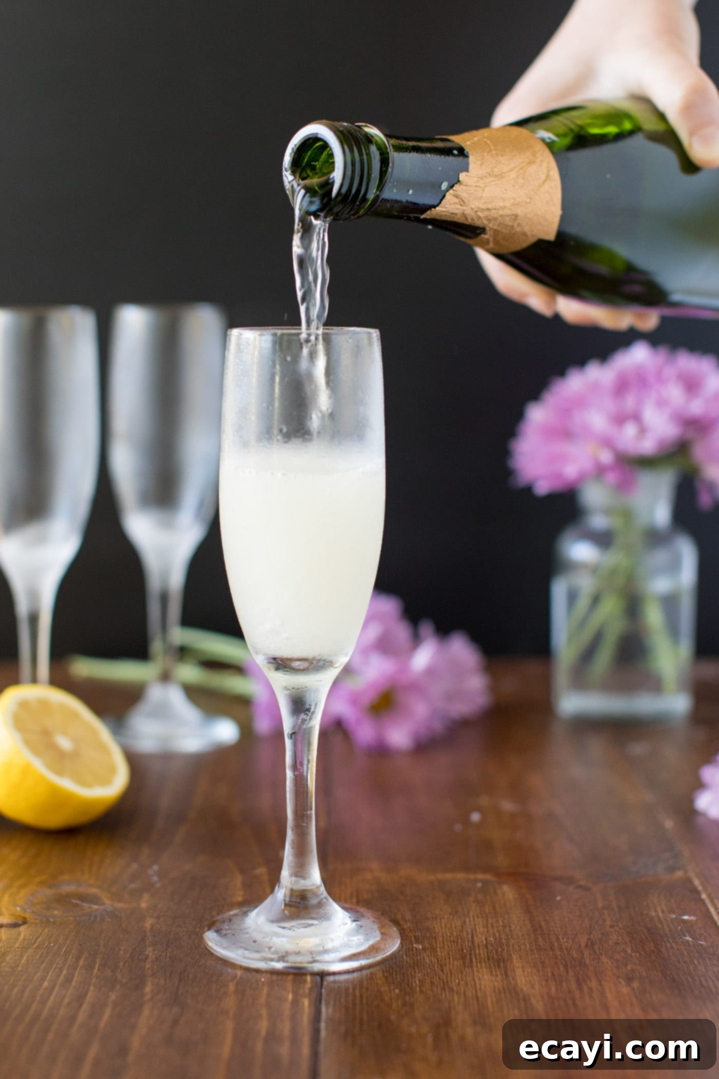 Effervescent Elan 3 Pouring sparkling champagne into a flute containing the gin and lemon mixture.