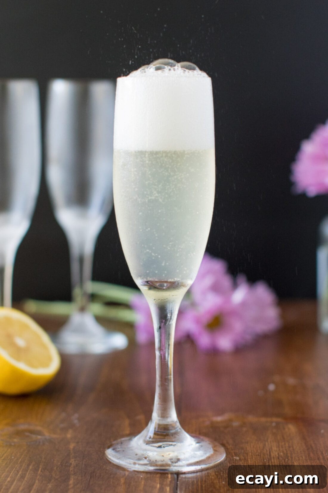 The refreshing sparkle of a French 75, a classic bubbly cocktail that's perfect for brunch, weddings, and holidays such as Mother's Day. Much like a spiked bubbly lemonade, the French 75 is a refreshing summertime cocktail as well. #french75 #french75recipe #french75cocktail #lemoncocktails #champagnecocktails #brunchcocktails #summercocktails Champagne fizzing and bubbling elegantly in a tall flute, illustrating the drink's effervescent quality.
