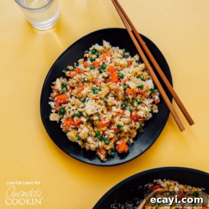 This Cauliflower Fried Rice is a delicious, low carb alternative to traditional fried rice. Keto friendly and super easy to make! #friedrice #keto #lowcarb #cauliflower #cauliflowerrecipes #cauliflowerrice #dinnersides #healthy #healthysides black bowl with cauliflower fried rice and chop sticks