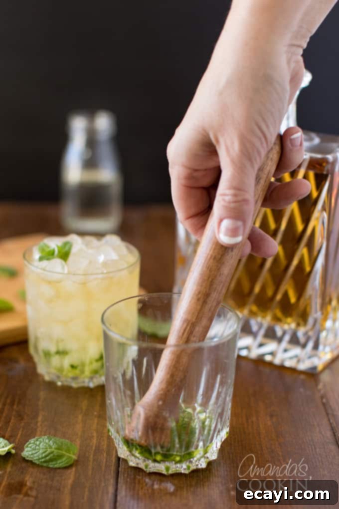 The classic Mint Julep, signature drink of the Kentucky Derby, is made with bourbon whiskey and served in a highball glass or a silver julep cup. Perfect your muddling technique with this cocktail recipe. Muddling mint leaves with simple syrup in a glass, demonstrating the gentle technique.