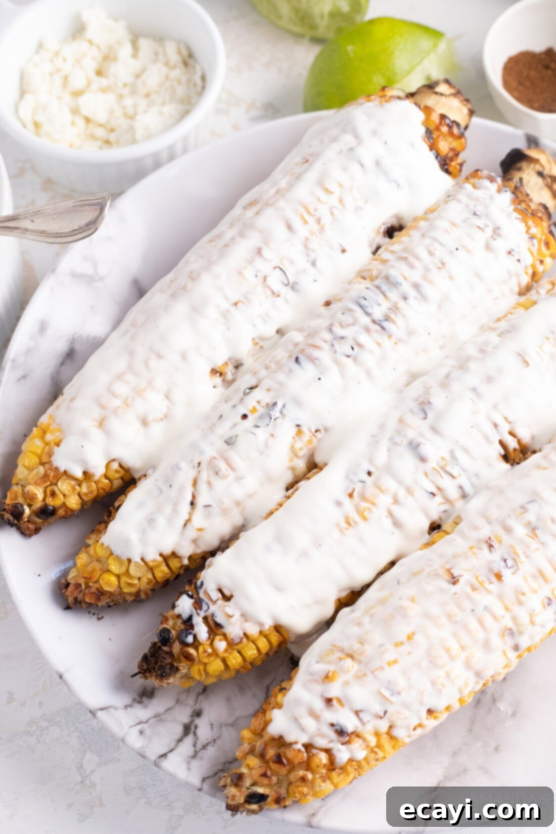 The secret to perfect Elotes: an even layer of creamy mayonnaise on each corn cob. This essential step ensures all the delicious cotija cheese, chili powder, and lime zest stick perfectly. #mayo #elotesdressing #cookinghacks #mexicanrecipes mayo on corn cobs