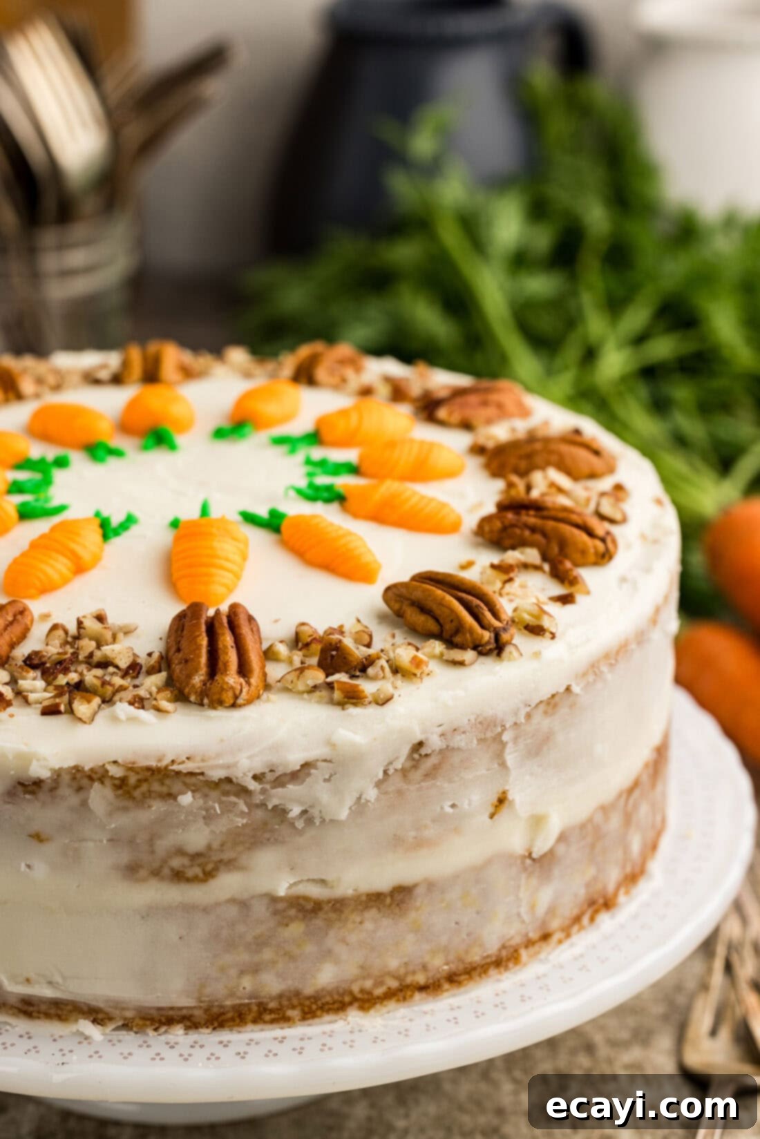 Spiced Carrot Delight 3 Close-up view of a beautifully decorated two-tiered carrot cake on a cake stand, featuring creamy white frosting, pecan garnishes, and delicate piped carrot decorations.