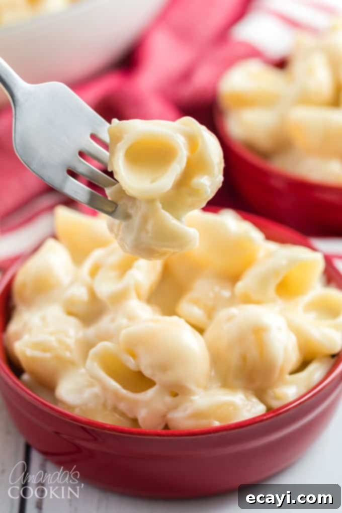 Learn how to make Panera mac and cheese at home! This creamy, delicious restaurant recipe is exactly what you're dying to make. #panera #macandcheese #macaroni #cheese #copycatrecipes #dinnersides A fork lifting a generous serving of homemade Panera mac and cheese, showcasing its rich, creamy sauce and perfectly cooked pasta.