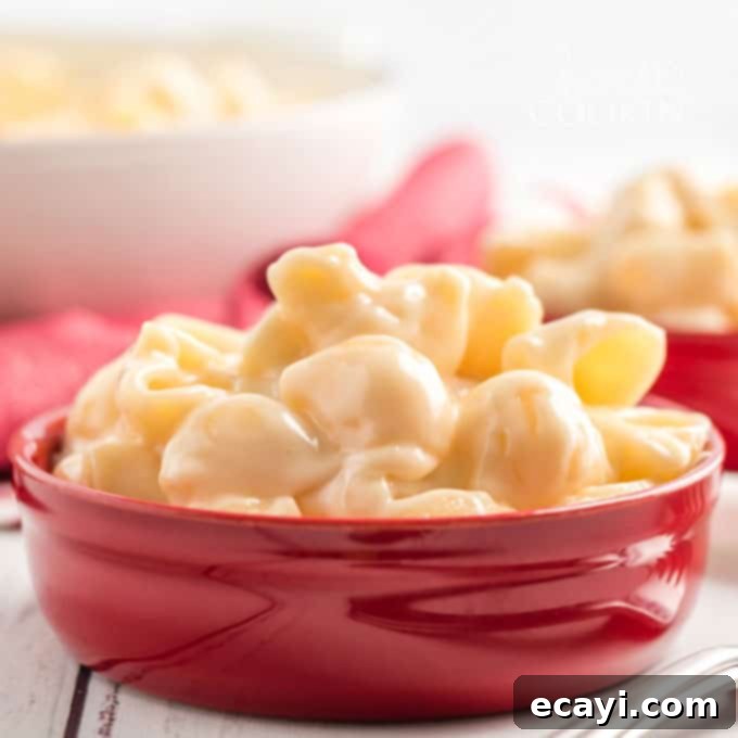Serve up happiness! This perfectly crafted homemade Panera mac and cheese is the ultimate comfort food for any occasion. #panera #macandcheese #macaroni #cheese #copycatrecipes #dinnersides A bright red bowl generously filled with homemade copycat Panera mac and cheese, showcasing its rich golden hue and inviting texture.