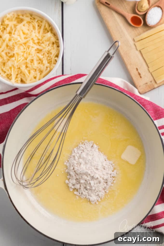 The foundation of creamy Panera mac and cheese: Melt butter, whisk in flour to create a smooth roux. #panera #macandcheese #macaroni #cheese #copycatrecipes #dinnersides A saucepan on low heat, showcasing melted butter and all-purpose flour being whisked together to form a perfect roux.