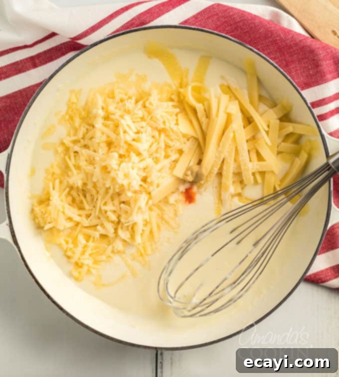 The secret blend revealed! Add American and sharp cheddar cheeses, Dijon, salt, and hot sauce to your sauce for Panera's flavor. #panera #macandcheese #macaroni #cheese #copycatrecipes #dinnersides A saucepan holding a creamy, smooth béchamel sauce, ready for the crucial addition of shredded cheeses and seasonings.