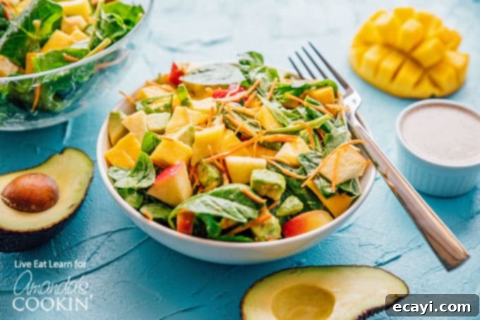 This delicious spinach salad is packed with protein-rich leafy spinach, sweet mango, and healthy fats from avocado. Perfect for summer! #spinachsalad #avocadosalad #mangosalad #summersalad #leafygreens #freshsaladrecipes #spinachsaladrecipes #meatlesssalad #amandascookin Spinach salad with mango and apples, beautifully arranged and ready to be served