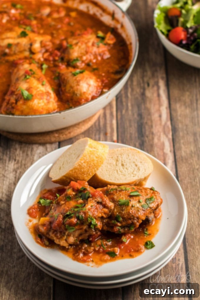 A plate of Stovetop Chicken Cacciatore served with crusty bread, showcasing the rich, slow-cooked chicken and savory sauce with onions, bell peppers, garlic, and capers. An ideal Italian comfort food. #stovetopdinner #weeknightmeals #dinnerrecipes #chicken #chickencacciatore #bellpeppers #chickendinner #familydinner chicken cacciatore on a plate with bread