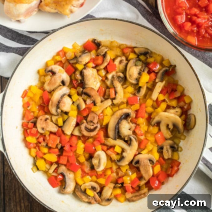 Sautéing bell peppers, onions, and mushrooms in the pan, building the aromatic base for Stovetop Chicken Cacciatore. #vegetables #sauteing #chickencacciatoreingredients bell pepper, onions, and mushrooms sauteed in pan