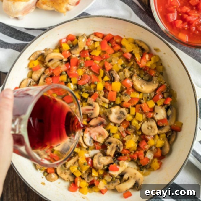 Deglazing the skillet with dry red wine, an essential step to loosen flavorful brown bits for the Stovetop Chicken Cacciatore sauce. #redwine #deglazing #saucebase Pouring wine into the skillet