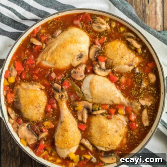 Nestling browned chicken pieces into the rich tomato and vegetable sauce for a long, slow simmer to create tender Stovetop Chicken Cacciatore. #slowcook #chickencacciatore #italiancomfort chicken pieces in sauce in pan