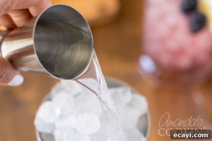 Mixing Gin for a Classic Bramble Cocktail Adding London Dry gin to a cocktail shaker filled with ice, preparing for a Bramble cocktail.