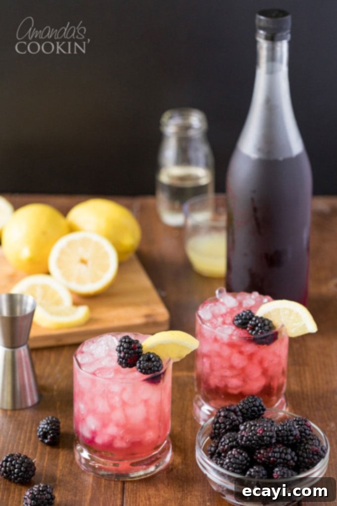 Enjoying Two Classic Bramble Cocktails with Crème de Mûre Two vibrant Bramble cocktails garnished with fresh blackberries and lemon, with a bottle of blackberry liqueur in the soft-focus background.