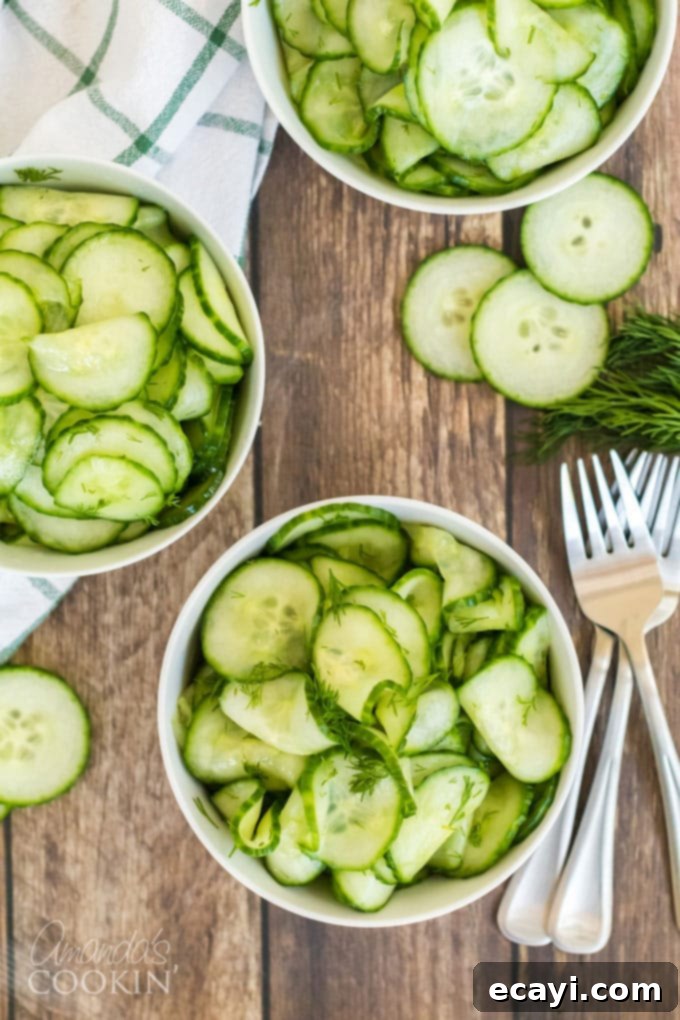 This classic cucumber salad is made with a homemade vinegar dressing and fresh dill. It's the vinegar cucumber salad your grandma used to make! #cucumbersalad #vinegarcucumbersalad #potluckrecipes #saladrecipes #cucumbersaladrecipes #amandascookin Individual serving bowls filled with fresh cucumber salad, garnished with extra dill, next to forks