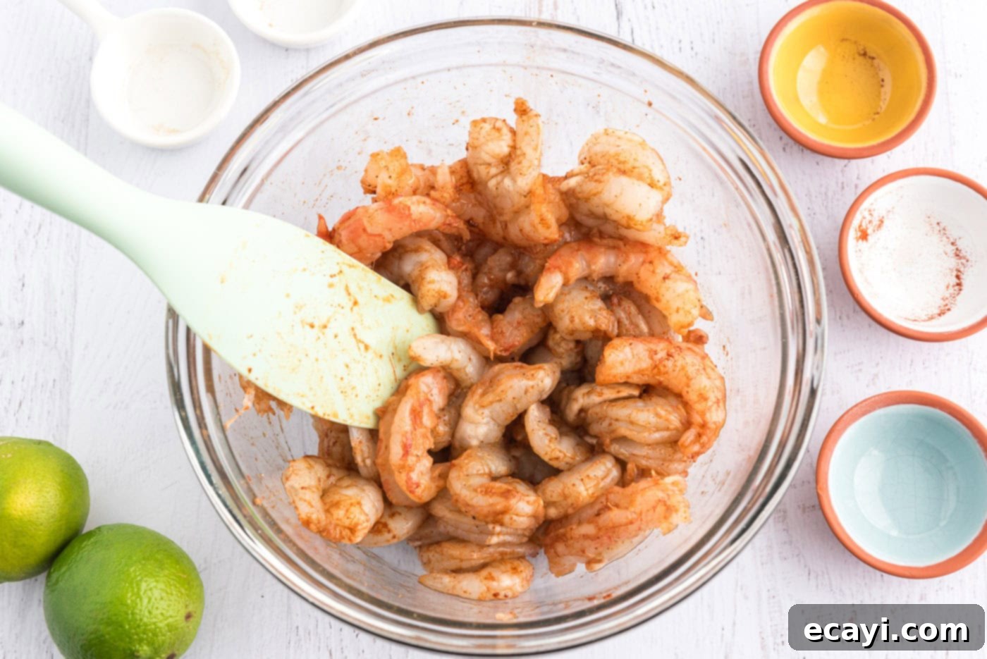 Zesty Shrimp Tacos 5 seasoned raw shrimp in a bowl with a rubber spatula