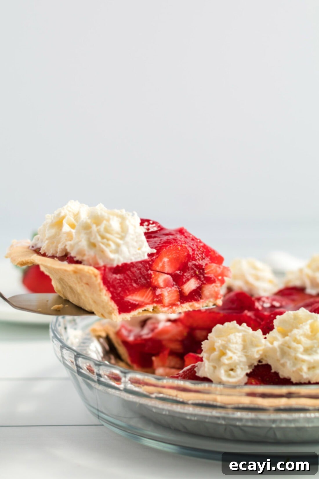 Taking a slice of easy Jello Strawberry Pie from the pan. A delectable slice of Jello Strawberry Pie being carefully removed from the pie plate, showcasing its perfectly set filling and fresh strawberries.