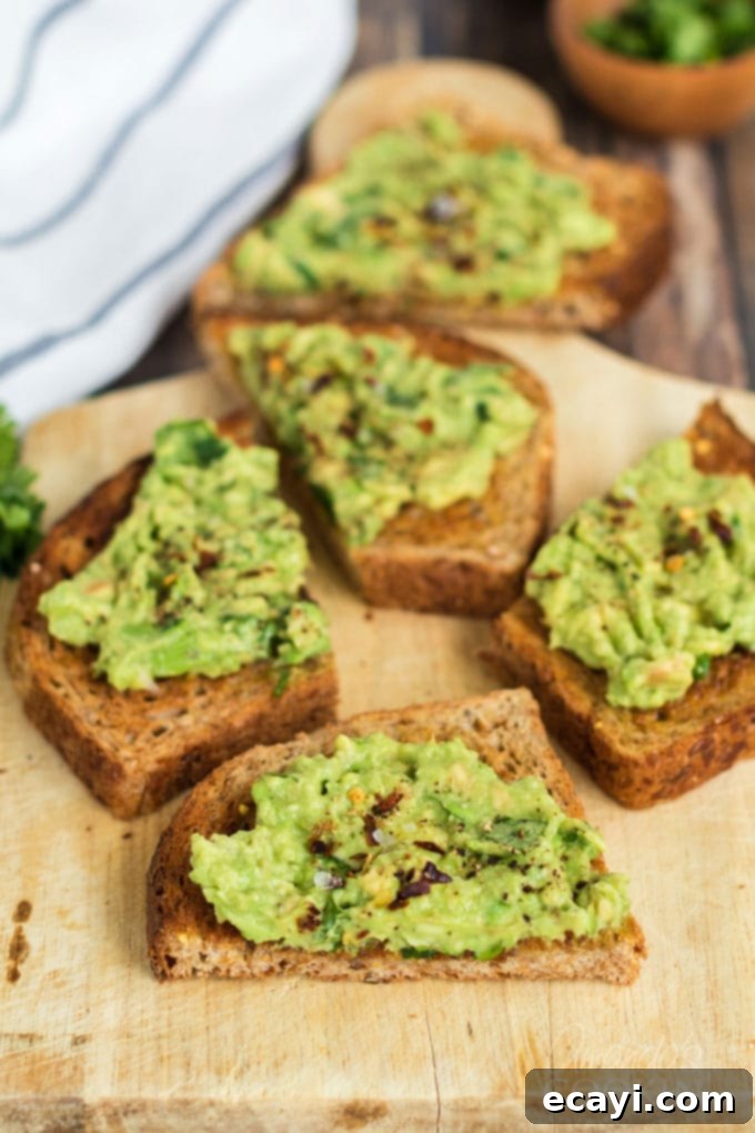 Avocado Toast 2 Slices of perfectly prepared avocado toast on a rustic cutting board, garnished with fresh cilantro and red pepper flakes.