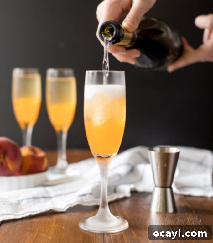 Commonly called a peach bellini, this combination of peach puree and Prosecco is served in a champagne flute and garnished with a fresh peach wedge. pouring Prosecco into champagne flute