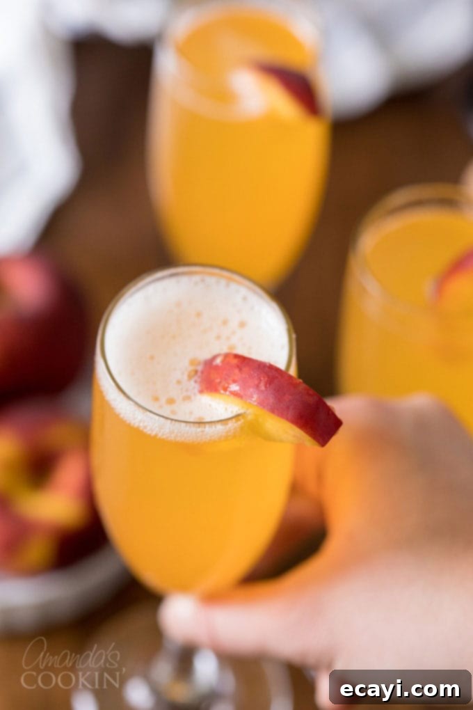 Commonly called a peach bellini, this combination of peach puree and Prosecco is served with a fresh peach wedge. lifting glass of bellini