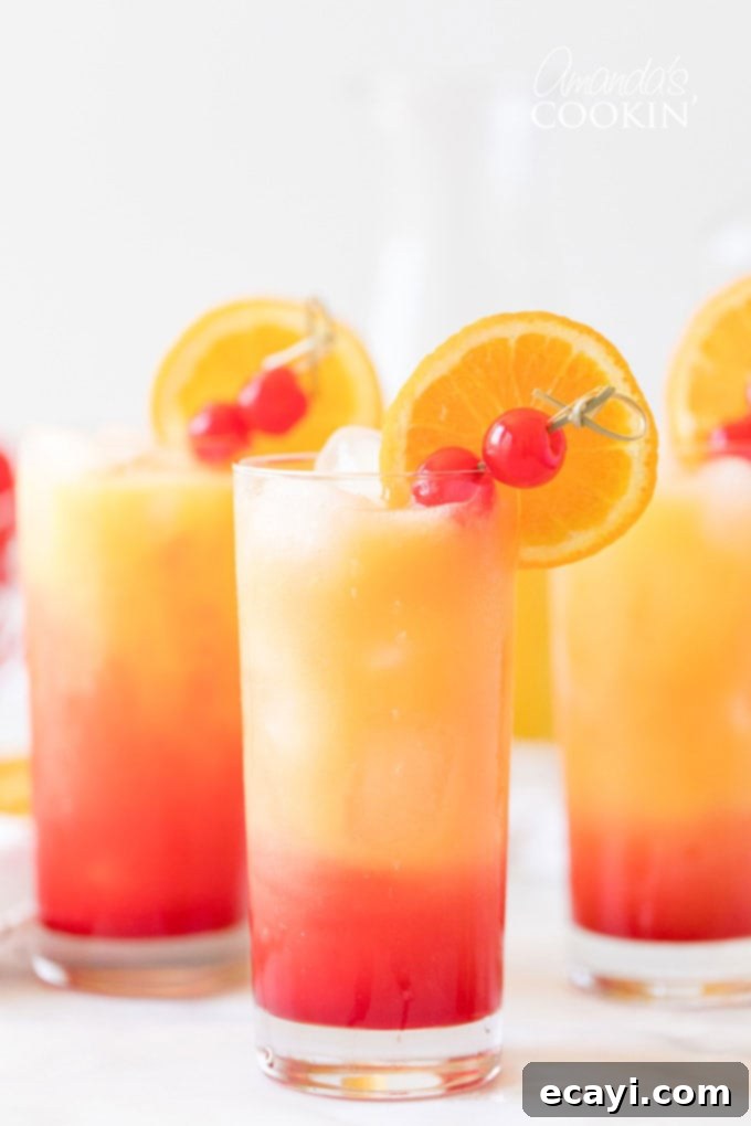 Classic Tequila Sunrise Cocktail: Tequila, Orange Juice, and Grenadine Recipe Three glasses of Tequila Sunrise cocktails, showcasing the vibrant layered colors of red and orange, garnished with orange slices and maraschino cherries. Perfect for a summer day.