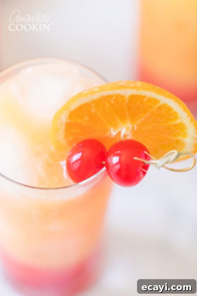 Garnishing Your Tequila Sunrise: Orange Slice and Maraschino Cherry Close-up of a single Tequila Sunrise glass, adorned with a fresh orange slice and a bright red maraschino cherry, highlighting the vibrant colors and appealing garnish.