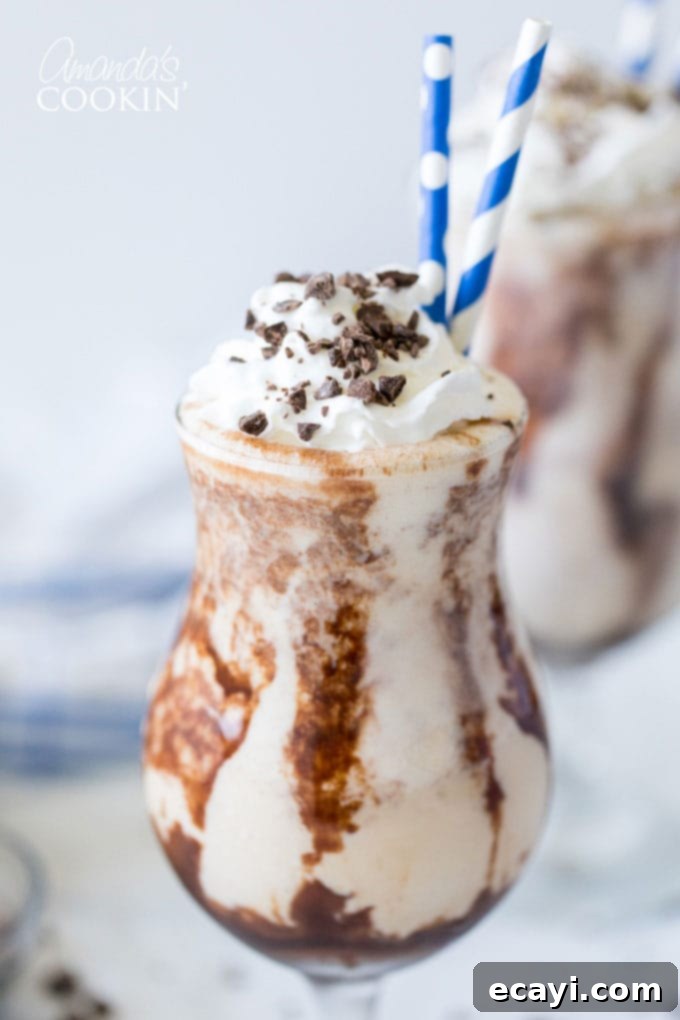The Frozen Mudslide is a delicious combination of Kahlua coffee liqueur, Baileys Irish cream, vodka, and ice cream. It's a summertime cocktail dream. #mudslide #frozenmudslide #mudslidecocktail #summercocktails #frozenmudslidemilkshake #amandascookin close up of mudslide in hurricane glass