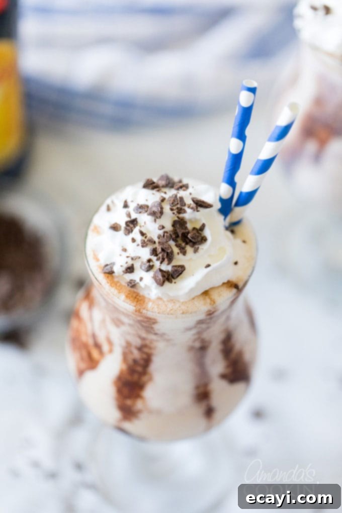 The Frozen Mudslide is a delicious combination of Kahlua coffee liqueur, Baileys Irish cream, vodka, and ice cream. It's a summertime cocktail dream. #mudslide #frozenmudslide #mudslidecocktail #summercocktails #frozenmudslidemilkshake #amandascookin hurricane glass with mudslide and two straws