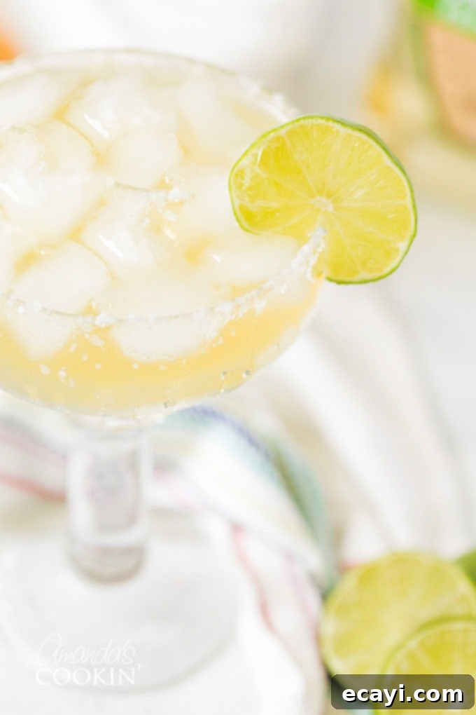 Learn how to make a margarita drink on the rocks. This classic cocktail is perfect any time of year, but especially fun for Cinco de Mayo and Margarita Day! #margarita #howtomakeamargarita #margaritadrink #margaritarecipe #margaritaontherocks #cincodemayo #cocktails #nationalmargaritaday #amandascookin CLOSE UP OF MARGARITA ON THE ROCKS with lime garnish and salt rim