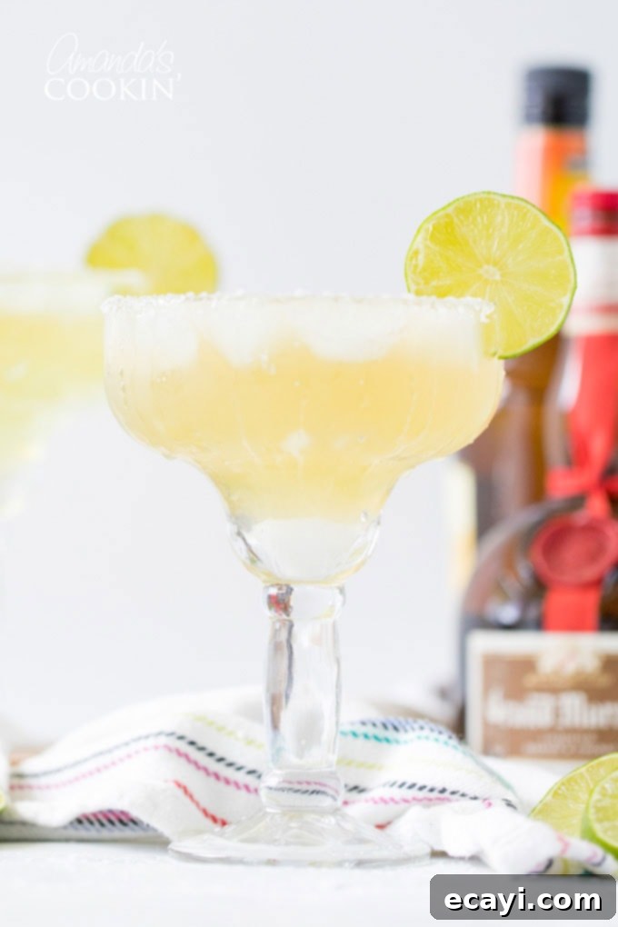 Learn how to make a margarita drink on the rocks. This classic cocktail is perfect any time of year, but especially fun for Cinco de Mayo and Margarita Day! #margarita #howtomakeamargarita #margaritadrink #margaritarecipe #margaritaontherocks #cincodemayo #cocktails #nationalmargaritaday #amandascookin margarita on the rocks in a glass with a lime garnish